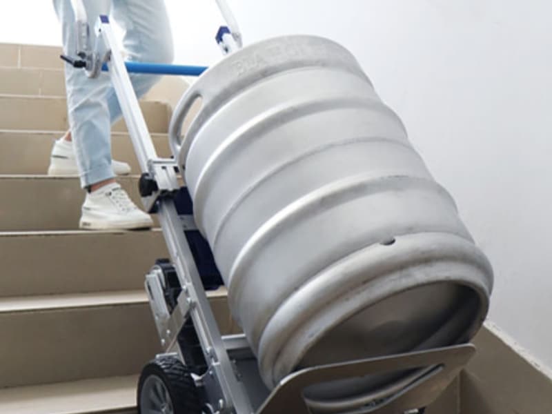 A motorised hand trolley smoothly moves a heavy beer keg down staircase steps.