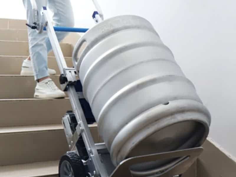 Motorised stair climber transporting heavy keg safely upstairs with ease.