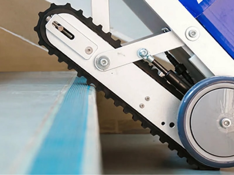 Powered stair climber hire equipment with rubber tracks gripping a stair edge for stability.
