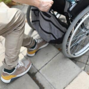 A person assisting a wheelchair user up outdoor steps, highlighting the need for safer stair climbing solutions for accessibility.